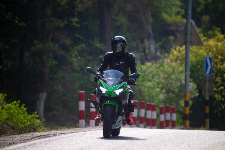 a man in black riding on the back of a motorcycle