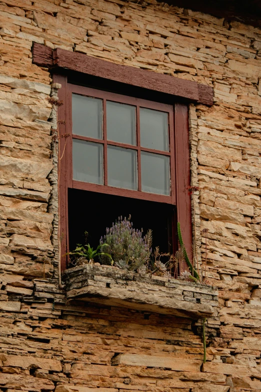 a window and wooden windowsill on a stone building