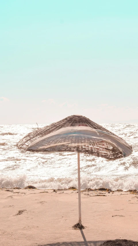 a beach umbrella sits on the sand of a beach