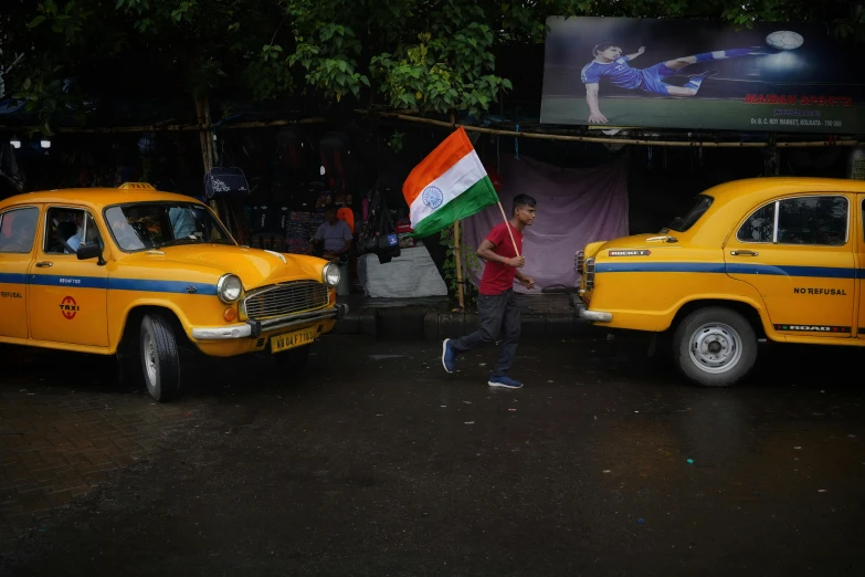 two cars parked on the street, with a man holding a flag in the middle