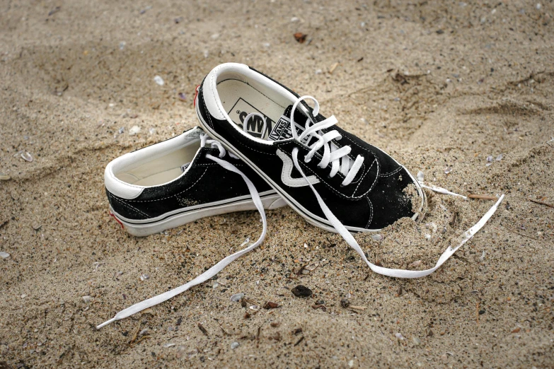 a black and white tennis shoe in the sand