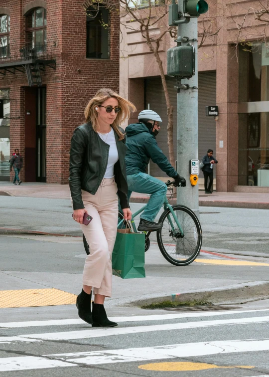 a woman in sunglasses rides a bicycle behind another man