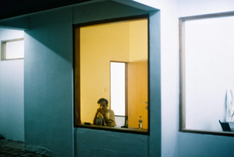 a woman looking out of a window with an empty vase on the ledge