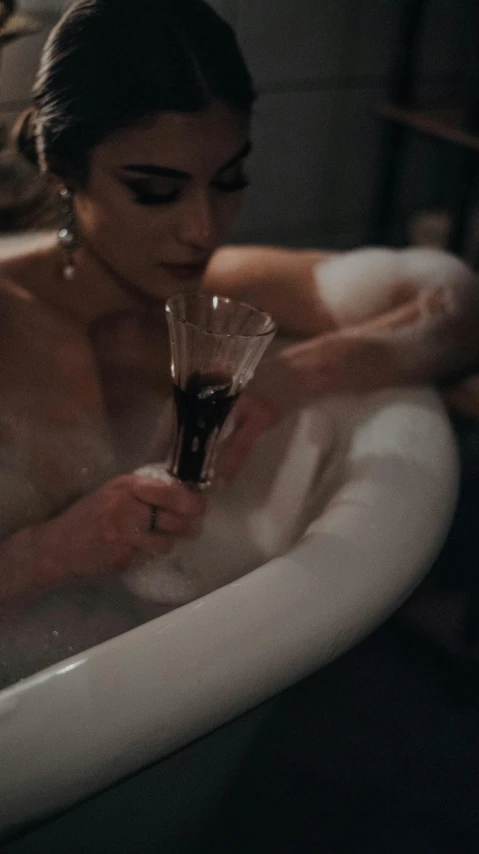 a woman drinking wine in an old fashioned bath tub