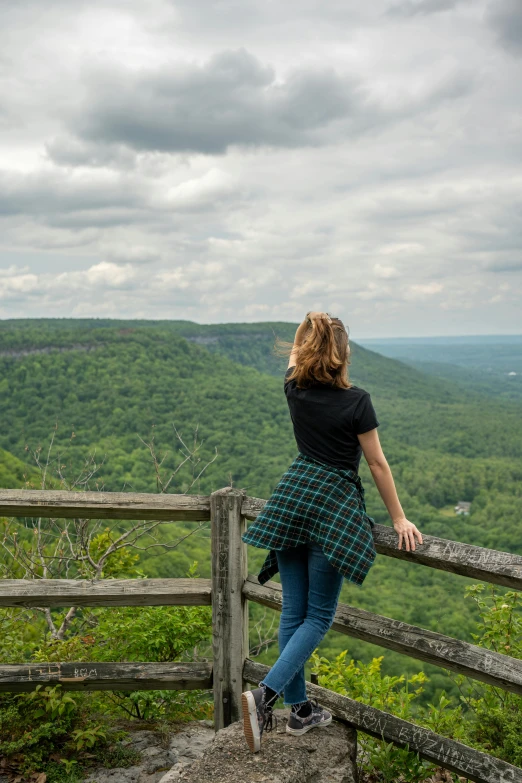 woman stands on a balcony overlooking the rolling mountains