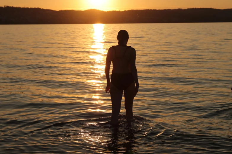 a person standing on a surf board in water at sunset