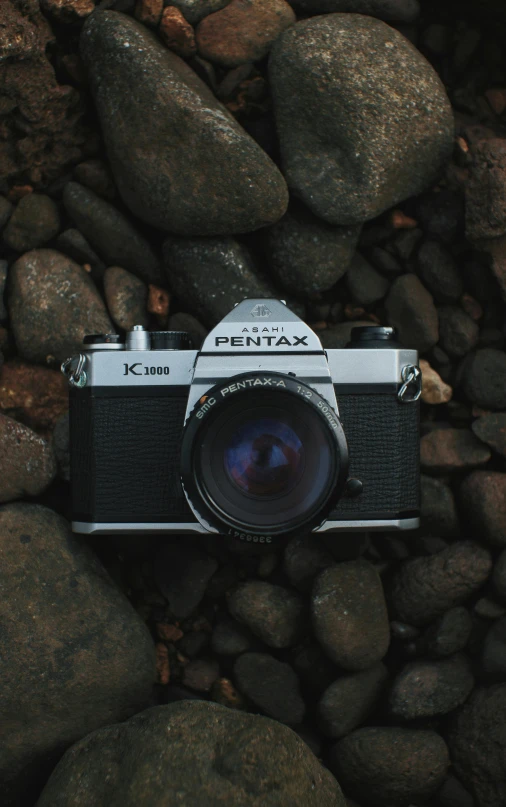 an old camera is sitting on rocks by the ocean