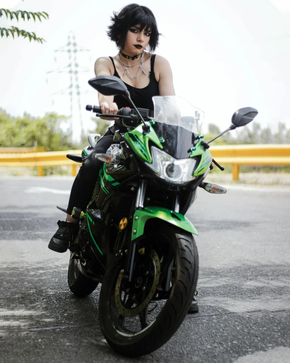 a beautiful young woman sitting on top of a green and black motorcycle