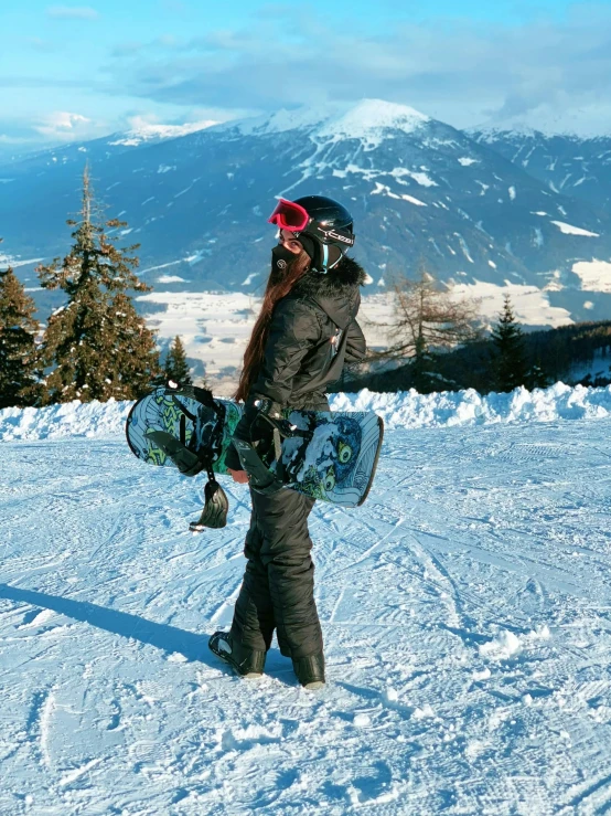 a person holding a snow board on a snowy mountain top