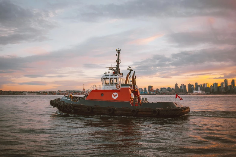 tugboat docked on the water with large city skyline behind it