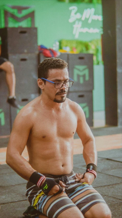 man sitting shirtless in front of a box - office