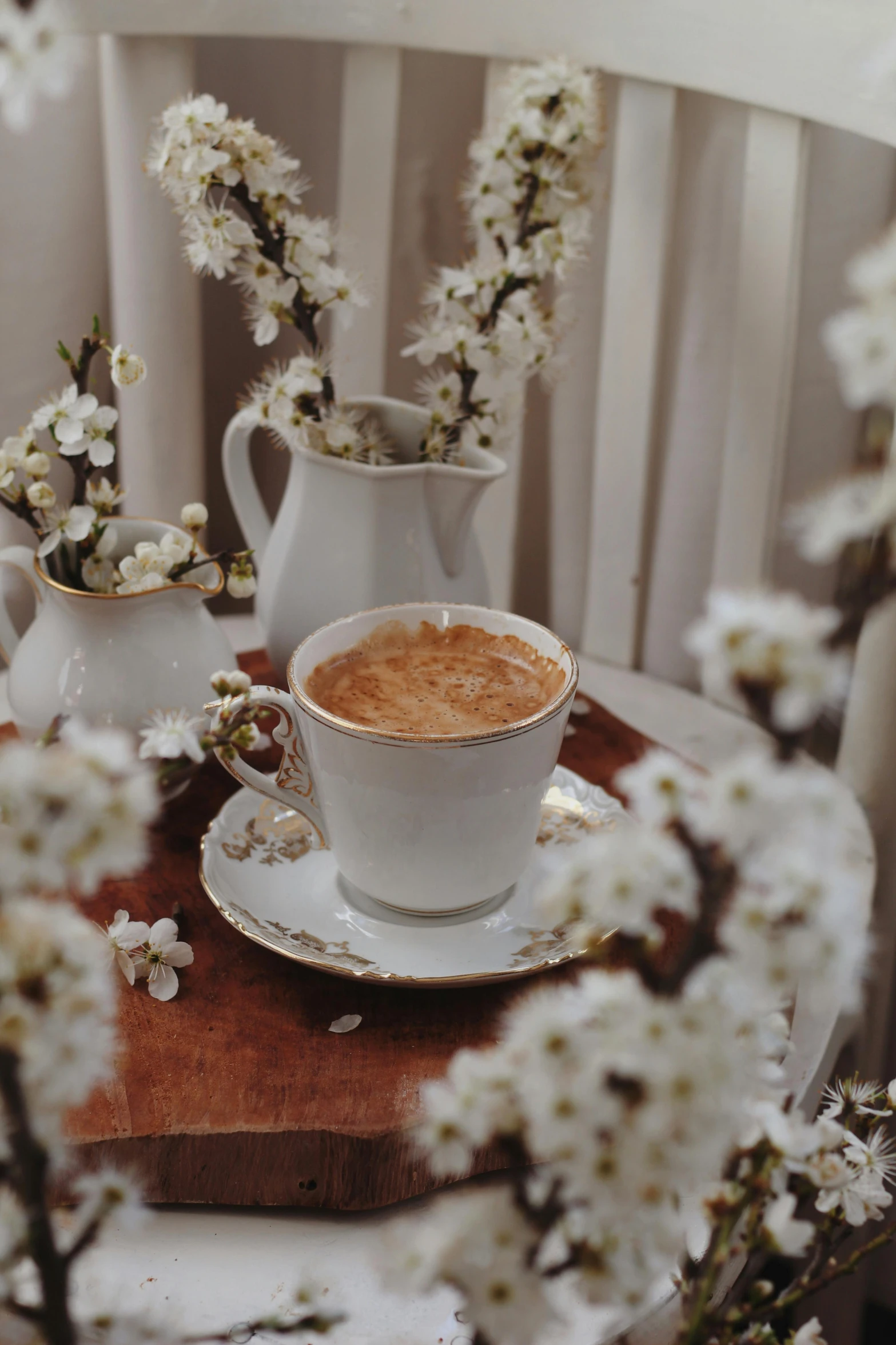 a cup of coffee and two white pitchers with flowers