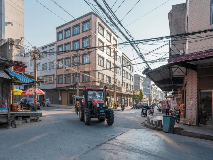 a man driving a tractor down a street next to tall buildings