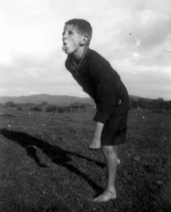 boy standing in grassy field blowing bubbles from his nose