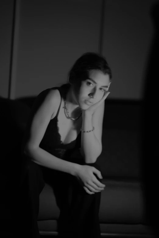 a young woman sits in the dark while looking down