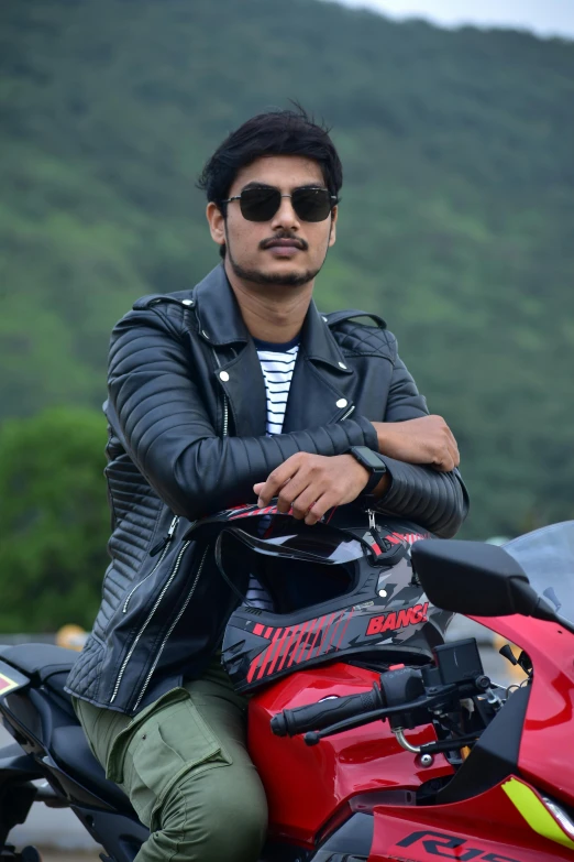 a man on top of a red motorcycle wearing a black jacket