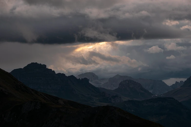 a dark sky with sun streaming out of between the clouds