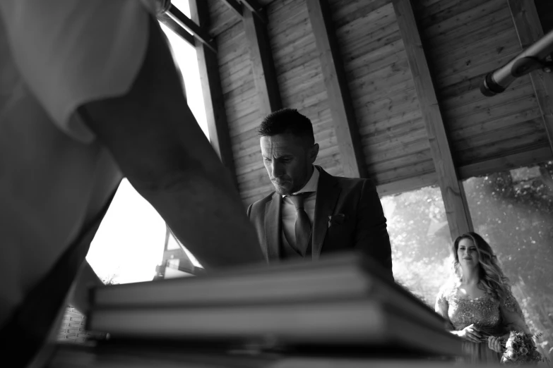 a man in suit and tie standing at a table