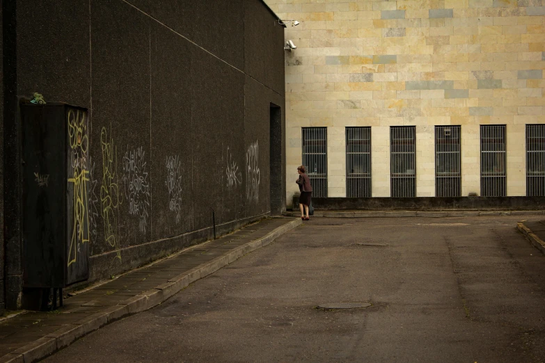 a person walking away from a building with graffiti on the wall