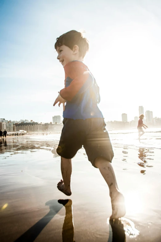 a young child running along the beach while other people are in the background