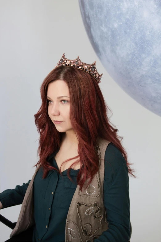 a girl with a tiara standing in front of a giant balloon