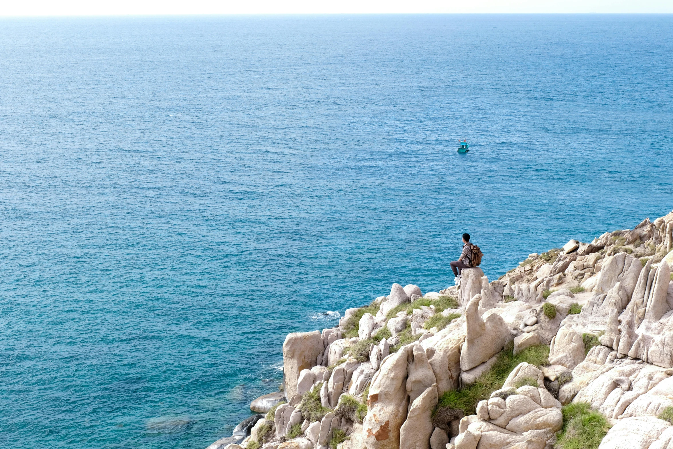 a person standing on rocks by a large body of water