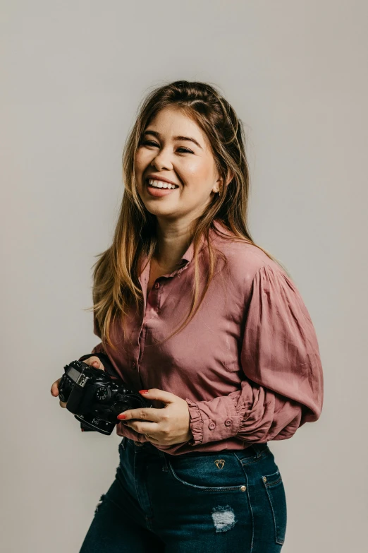 a woman smiling while she holds her camera