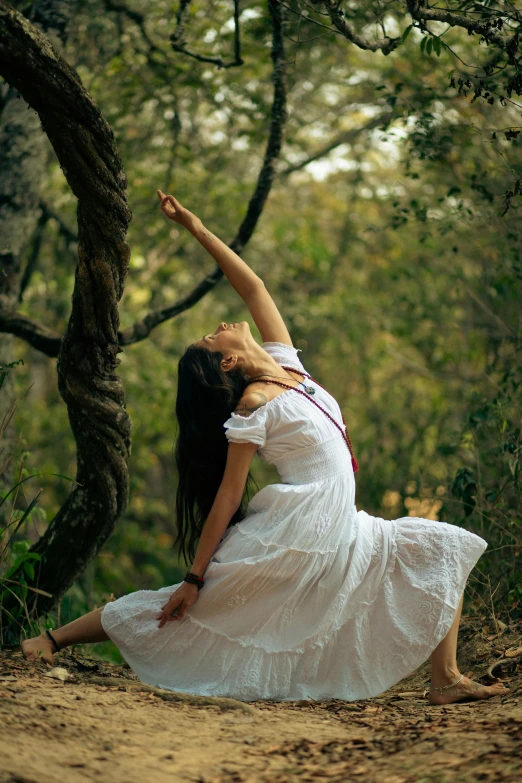 a young woman is doing an acrobatic pose in the woods