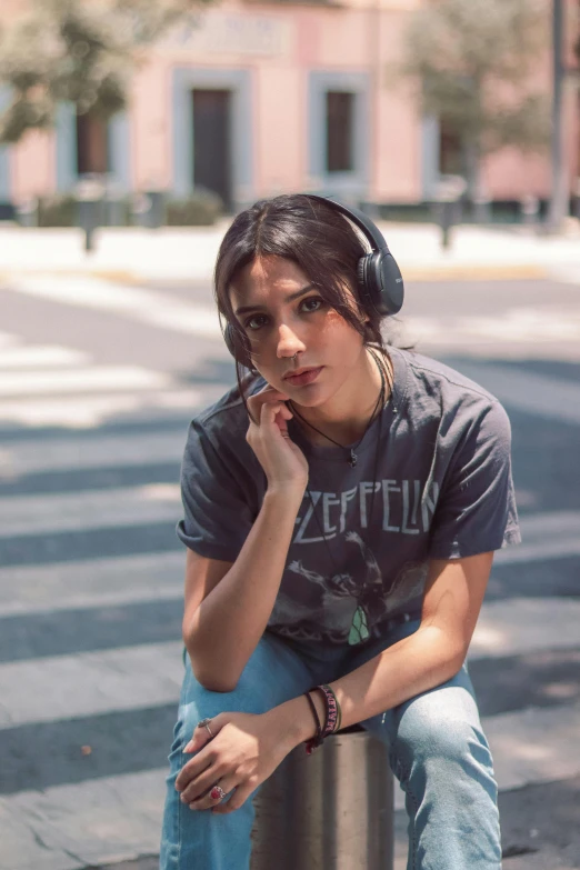 a girl is sitting on the curb while listening to music