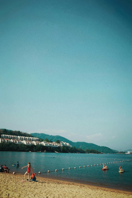 a person is sitting on the beach next to a lake