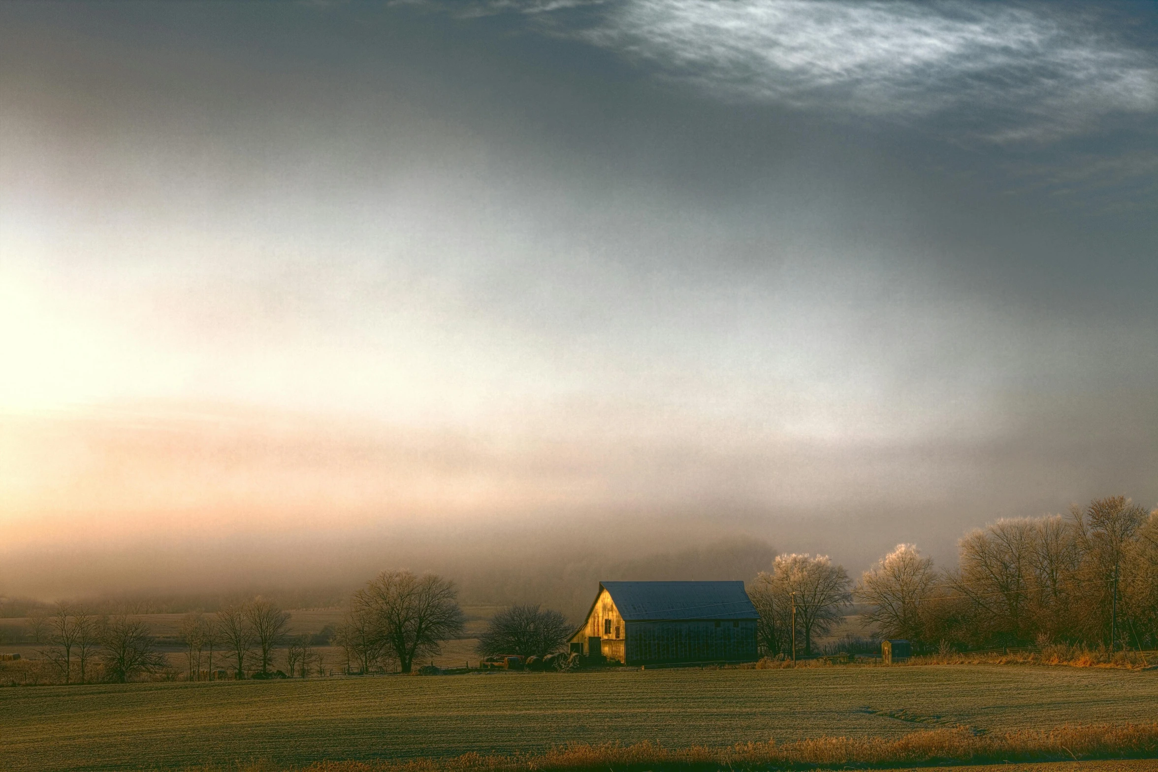 a large open field with a lone house on it