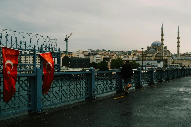 a man walking down a sidewalk near the edge of a bridge