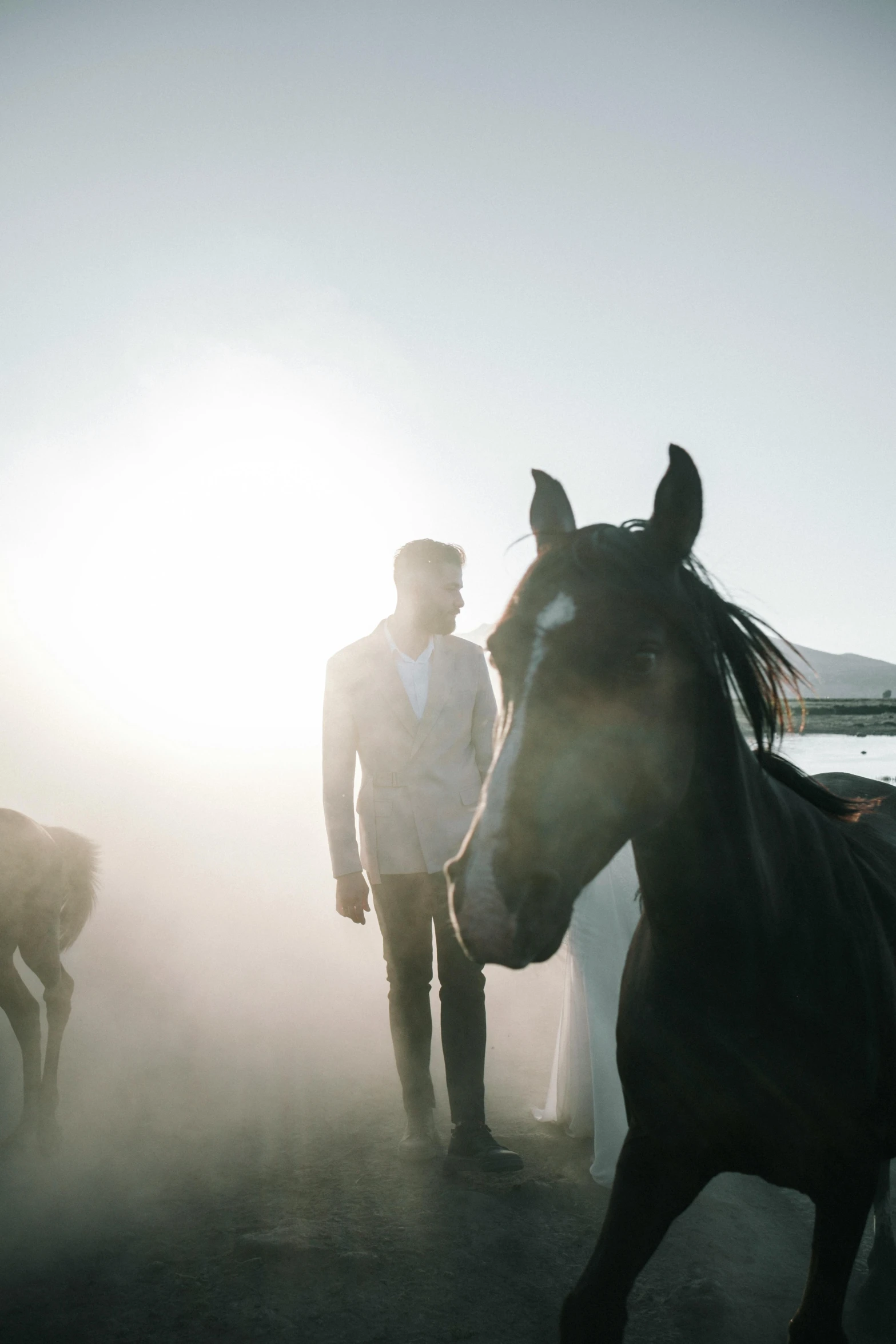 two men in white shirts and some horses