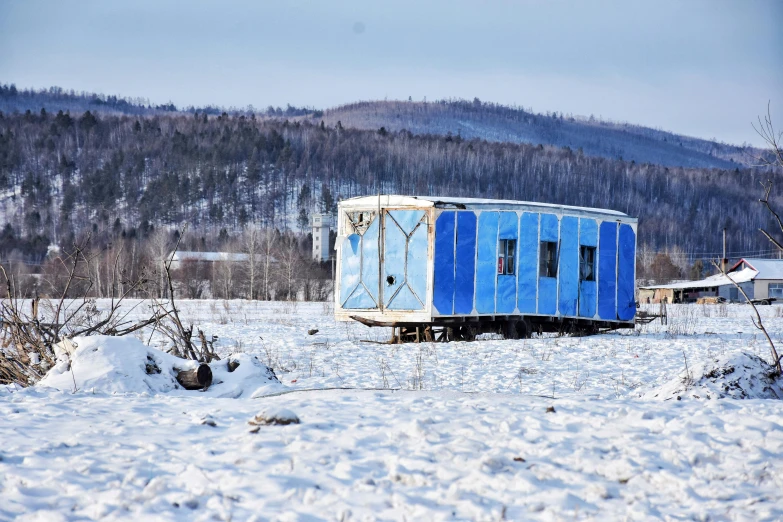 a blue, gray and white boxcar in the snow