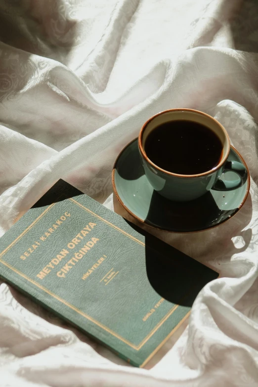 a close up of a cup of coffee next to an open book