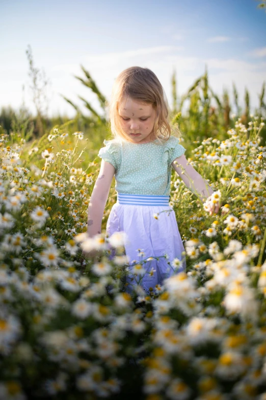 a little girl walking through a field with white flowers