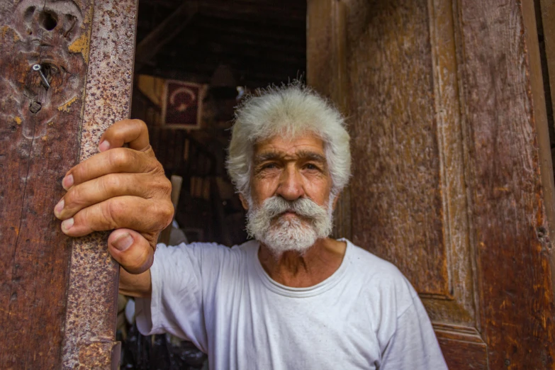 a man with a long gray beard standing in front of a doorway