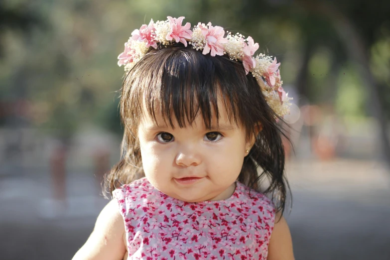 little girl with a pink dress has a pretty pink flower crown on her head