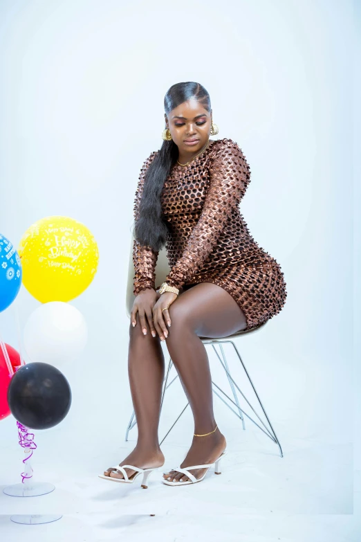 a woman is dressed in a sheer dress sitting on a chair with balloons