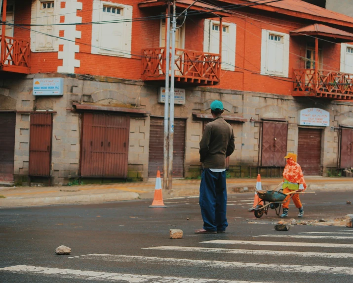 two people standing on the side of a road next to some orange houses