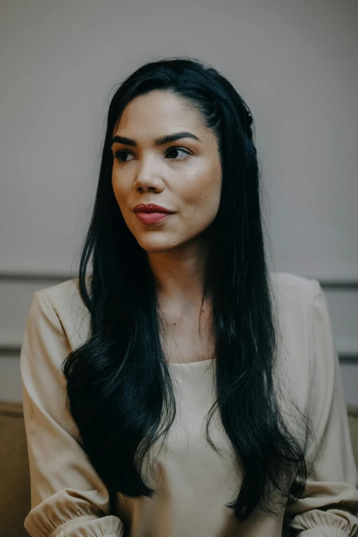 an oriental woman sitting with long hair and looking at the camera