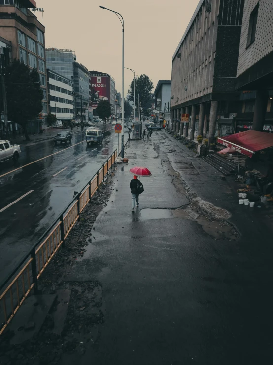 a person walking down a wet road holding an umbrella