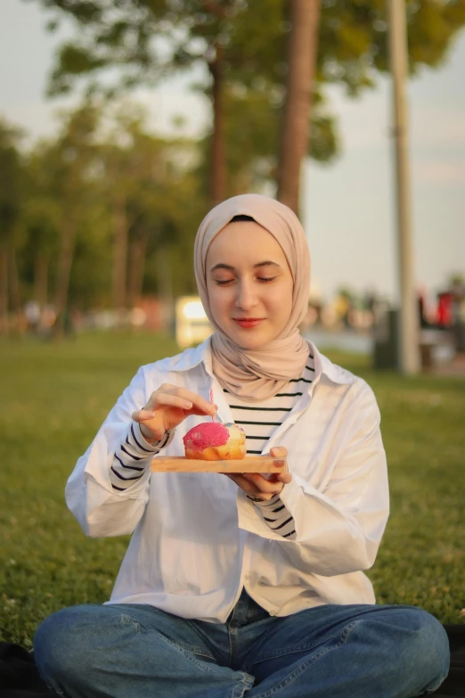 a woman sitting in the grass eating an apple