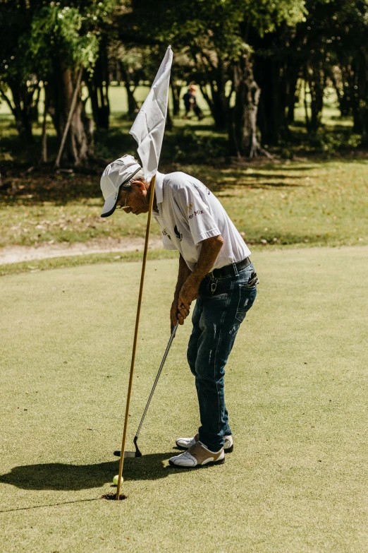 a man putting a flag in the green with his hat