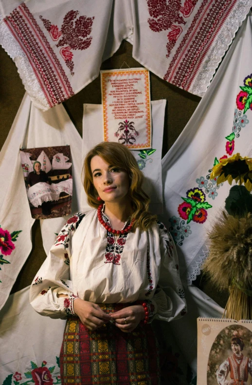 a woman stands next to a bunch of cloth and embroidery