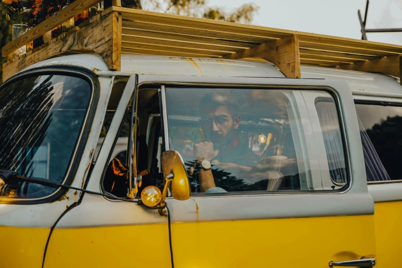 an old yellow and white van with a person sitting inside