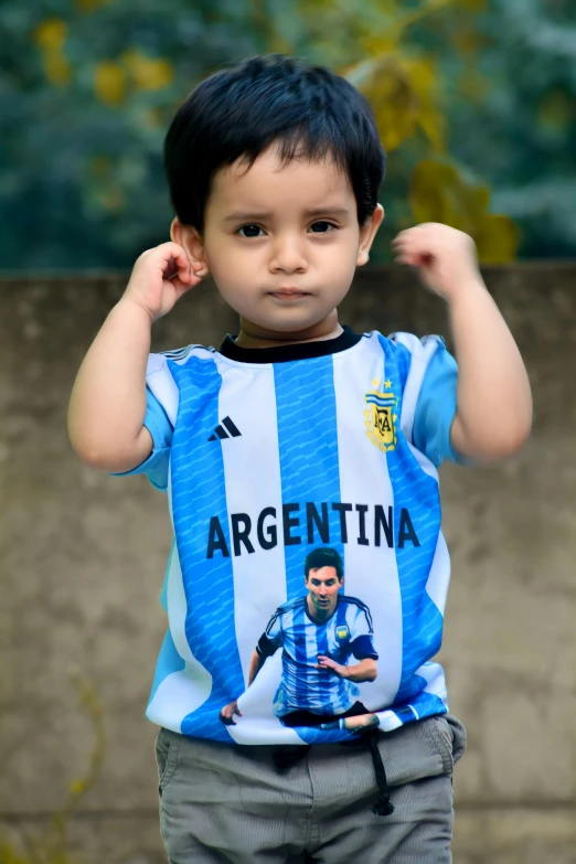 small boy holding arm over his head and wearing blue and white shirt