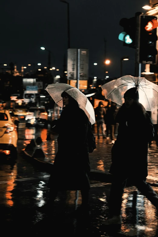 people with umbrellas on a wet street at night