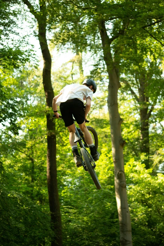 a person on a bike doing a jump over the forest