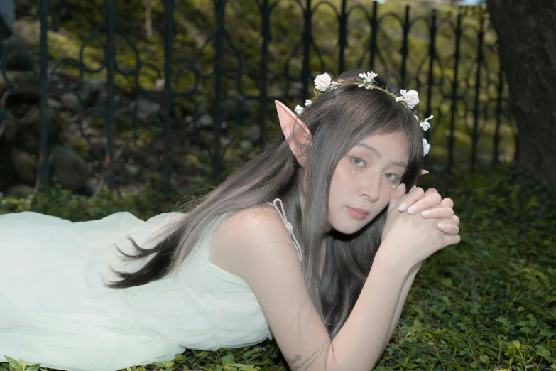 the young woman poses near the fence in the grass